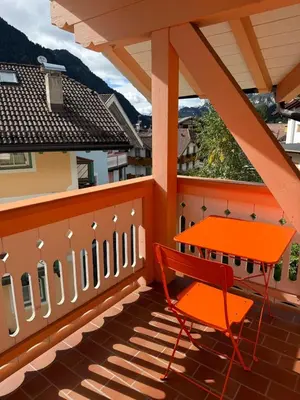 an orange chair and a table on a balcony at Elegante Appartamento in Campitello fi Fassa in Campitello di Fassa