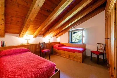 a bedroom with two red beds and a window at Villa Allegra Mountain view in Cortina dʼAmpezzo