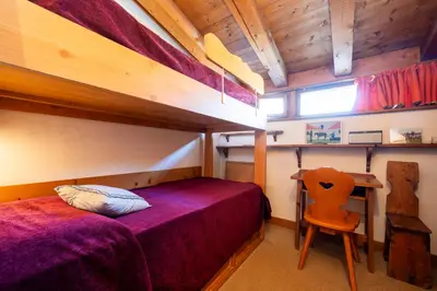 a bedroom with a bed and a desk with a chair at Villa Allegra Mountain view in Cortina dʼAmpezzo