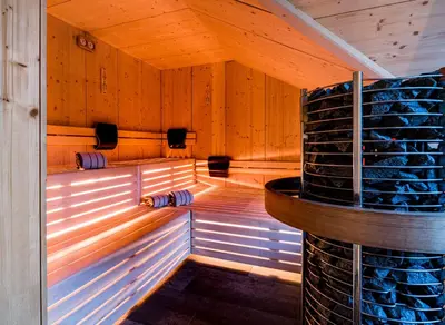 an empty sauna with a stone wall and wooden walls at Apartment Vernel in Santa Cristina in Val Gardena