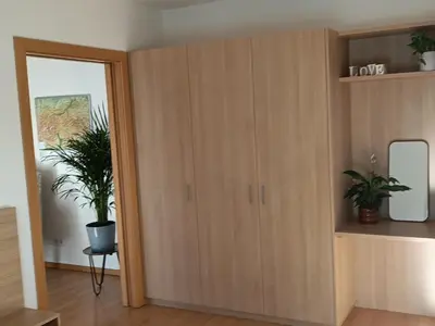 a room with a large wooden cabinet with two potted plants at Villa Ehrenburg - Private Apartments in Merano