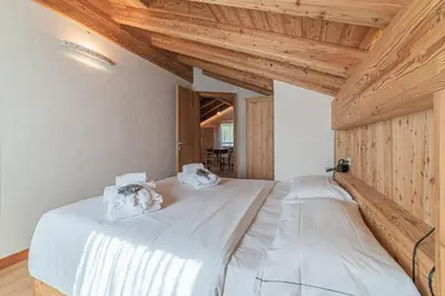 two beds in a room with wooden ceilings at Chalet Dolomites Heart in Feder