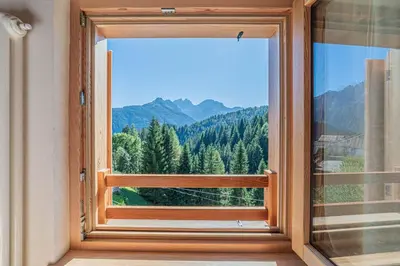 an orange chair in a bedroom with wooden ceilings at Chalet Dolomites Heart in Feder
