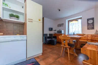 a kitchen and dining room with a table and a counter at Appartamento al Rio in Moena