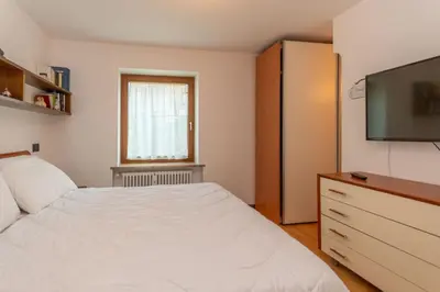 a bedroom with a bed and a flat screen tv at Appartamento al Rio in Moena