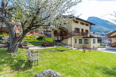 a yard with a tree and a building at Appartamento al Rio in Moena