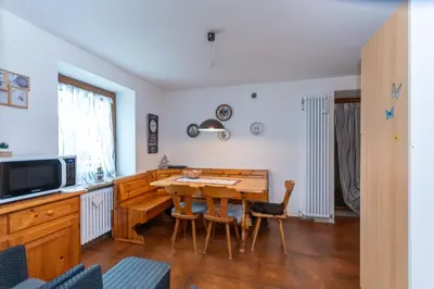 a kitchen with a wooden table and chairs in a room at Appartamento al Rio in Moena