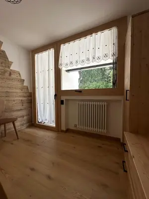 an empty room with a window and a staircase at Cèsa Sabrina in Moena