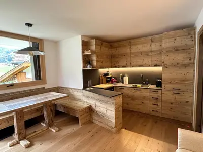 a kitchen with wooden cabinets and a large window at Cèsa Sabrina in Moena