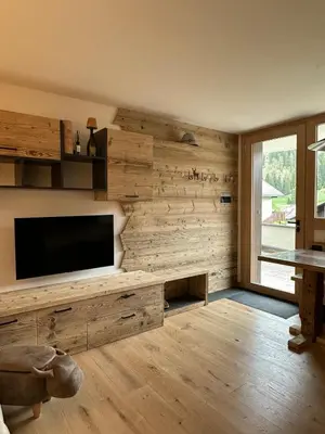 a living room with wooden walls and a flat screen tv at Cèsa Sabrina in Moena