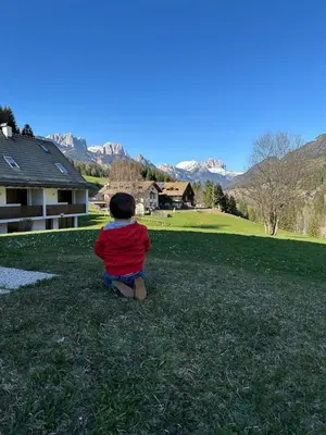 a little boy sitting on the grass in a field at Cèsa Sabrina in Moena