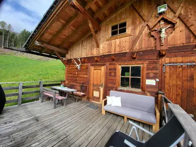 a wooden cabin with a bench on a deck at Almliesl WELS-424 in Monguelfo