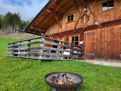 a fire pit in front of a wooden cabin at Almliesl WELS-424 in Monguelfo