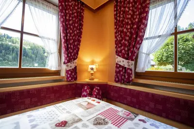 a bedroom with a bed and two windows at Apartments Miara in Santa Cristina in Val Gardena