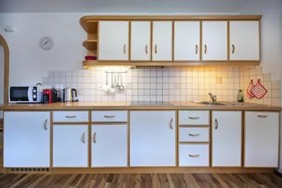 a kitchen with white cabinets and a counter at Apartments Miara in Santa Cristina in Val Gardena