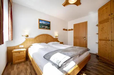 a bedroom with a large bed with a wooden headboard at Apartments Miara in Santa Cristina in Val Gardena