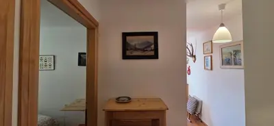 a hallway with a table and a clock on the wall at Condominio de Rocia in Moena