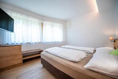 a bedroom with two beds and a flat screen tv at Apartments Cesa Ploner in Ortisei