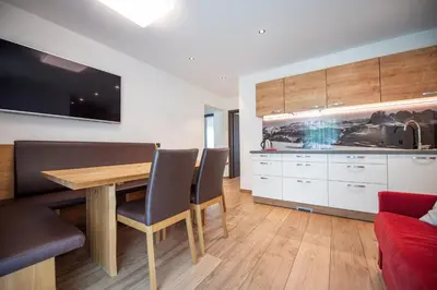 a kitchen and living room with a wooden table and chairs at Apartments Cesa Ploner in Ortisei
