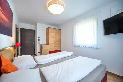 a bedroom with two beds and a flat screen tv at Apartments Cesa Ploner in Ortisei
