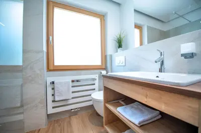 a bathroom with a sink and a toilet and a window at Apartments Cesa Ploner in Ortisei
