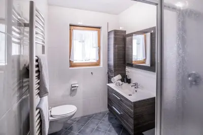 a white bathroom with a toilet and a sink at Erika Suites & Lofts Chalet in Stanghe