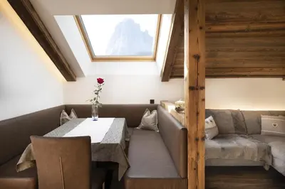 a room with a table and a couch and a window at Apartments Rondula in Santa Cristina in Val Gardena