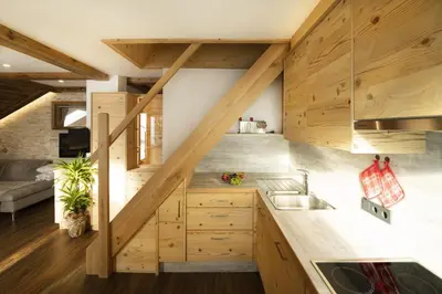 an attic kitchen with wooden cabinets and a staircase at Apartments Rondula in Santa Cristina in Val Gardena