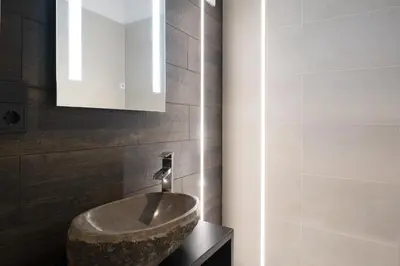 a bathroom with a stone sink and a mirror at Apartments Rondula in Santa Cristina in Val Gardena