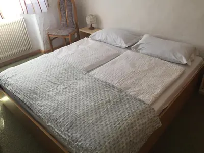 a large bed in a bedroom with a chair at Platzlhof in Appiano sulla Strada del Vino