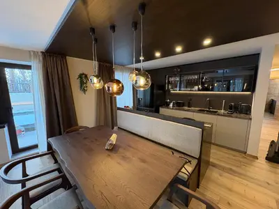 a dining room with a wooden table and a kitchen at GARDEN SUITE appartment in Valdaora di Sopra
