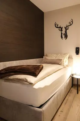 a bedroom with a large white bed with a headboard at GARDEN SUITE appartment in Valdaora di Sopra