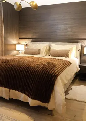 a bedroom with a large bed with a brown blanket at GARDEN SUITE appartment in Valdaora di Sopra