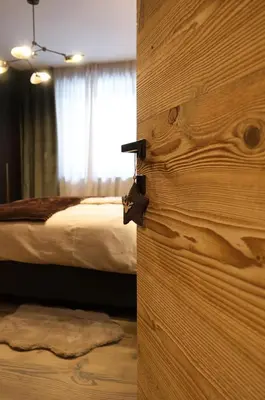 a bedroom with a bed and a wooden door at GARDEN SUITE appartment in Valdaora di Sopra