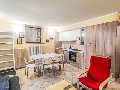 a kitchen with a table and a red chair at Apartment Ciasa Tella by Interhome in Moena