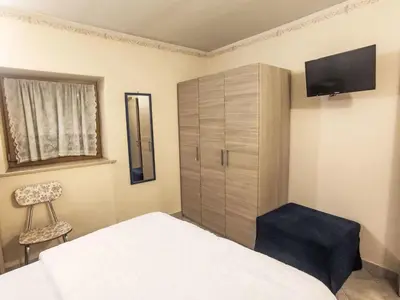 a bedroom with a bed and a cabinet and a chair at Apartment Ciasa Tella by Interhome in Moena