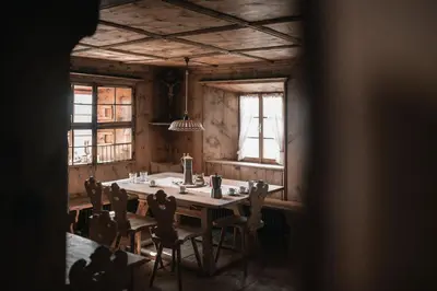 a dining room with a table and chairs and windows at South Tyrol Lodge With Mountain Views in Villandro