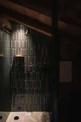 a bathroom with a shower with a black tiled wall at South Tyrol Lodge With Mountain Views in Villandro
