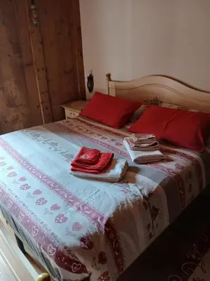 a bed with red pillows and towels on it at BeB LA STUBE DEI PARTEL in Ziano di Fiemme