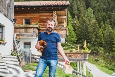 a man holding a baseball in front of a cabin at Ferienwohnungen Wiesbauer in Schenna