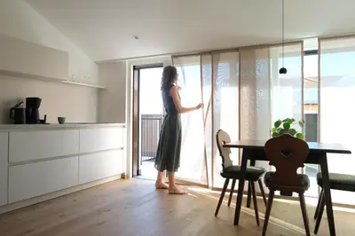 a woman is looking out of a window in a kitchen at Kreuz Appartement in Rifiano