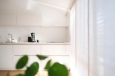 a kitchen with white cabinets and a sink and a plant at Kreuz Appartement in Rifiano