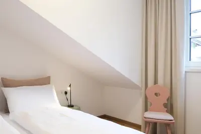 a bedroom with a bed and a chair next to a window at Kreuz Appartement in Rifiano