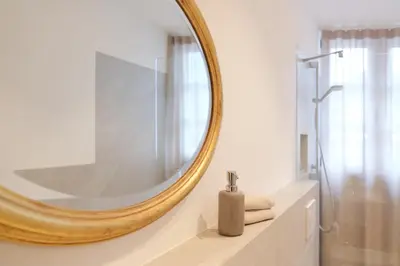 a bathroom with a large mirror on the wall at Kreuz Appartement in Rifiano