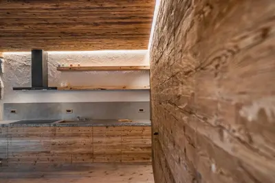 a kitchen with a wooden wall and a sink at Chalet Lumiere by Elite Villas in Livinallongo del Col di Lana