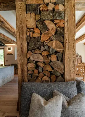 a stone wall with a pile of logs at Chalet Lumiere by Elite Villas in Livinallongo del Col di Lana
