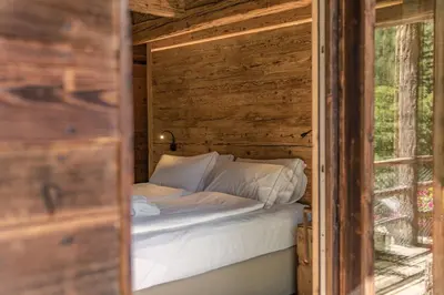a bed in a wooden room with a window at Chalet Lumiere by Elite Villas in Livinallongo del Col di Lana