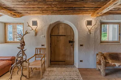 a room with a door and a chair and a couch at Chalet Lumiere by Elite Villas in Livinallongo del Col di Lana