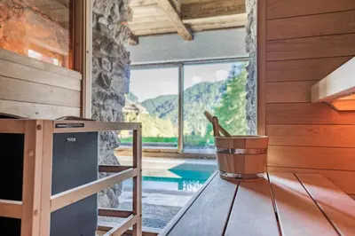 a room with a view of a pool and a table at Chalet Lumiere by Elite Villas in Livinallongo del Col di Lana