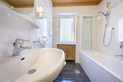 a white bathroom with a tub and a sink and a bath tub at Pivan Apartments in Selva di Val Gardena